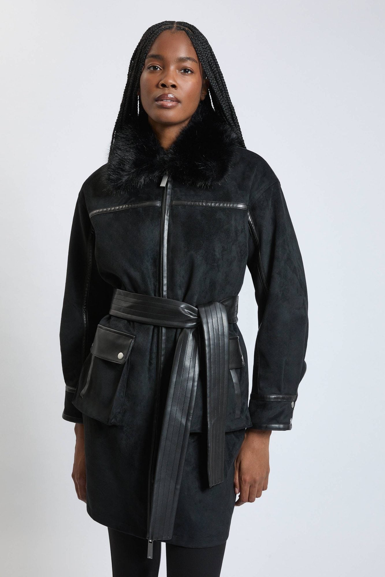 Woman wearing black denim jacket with fur collar and leather belt, styled as a dress