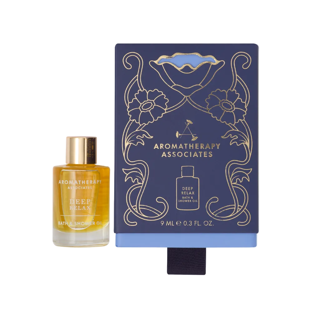 Deep Relax bath and shower oil bottle next to its decorative navy gift box packaging