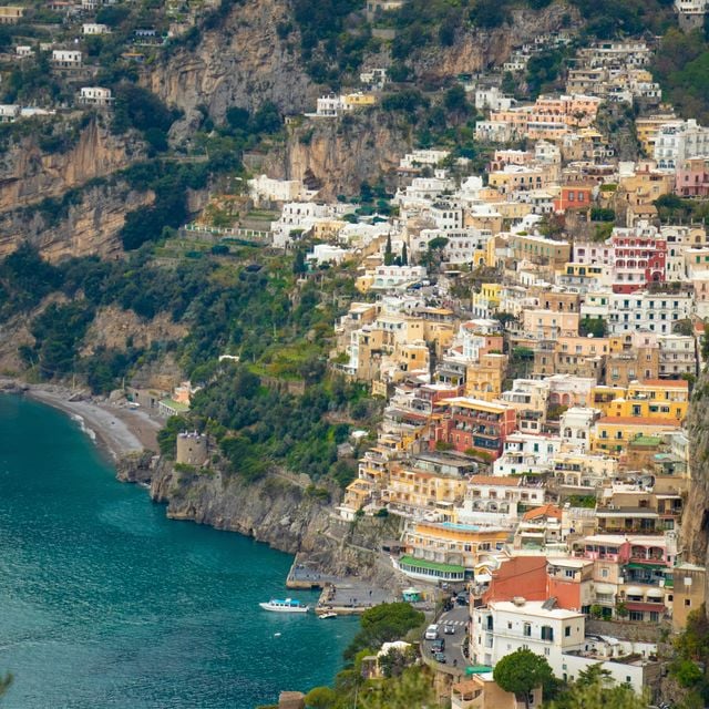 Colorful cliffside village with pastel buildings cascading down rocky terrain toward turquoise Mediterranean water