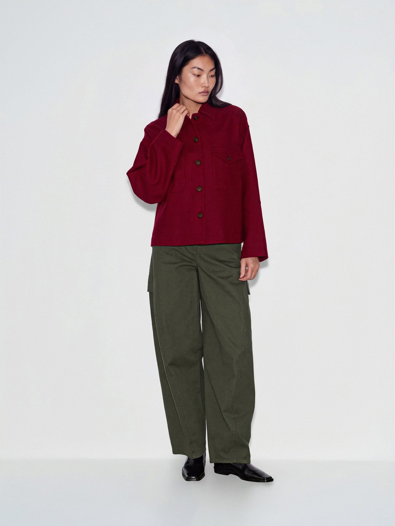 Woman wearing burgundy button-up jacket with olive cargo pants and black loafers